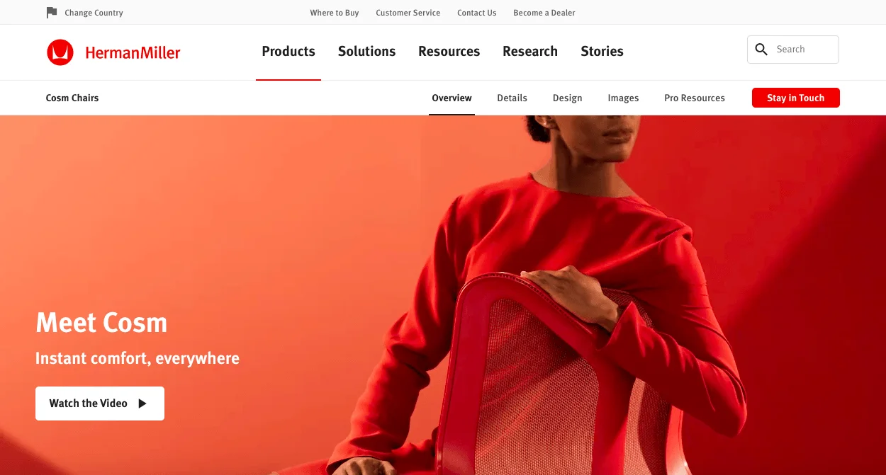 Person sitting on a Herman Miller Cosm chair with a red background.