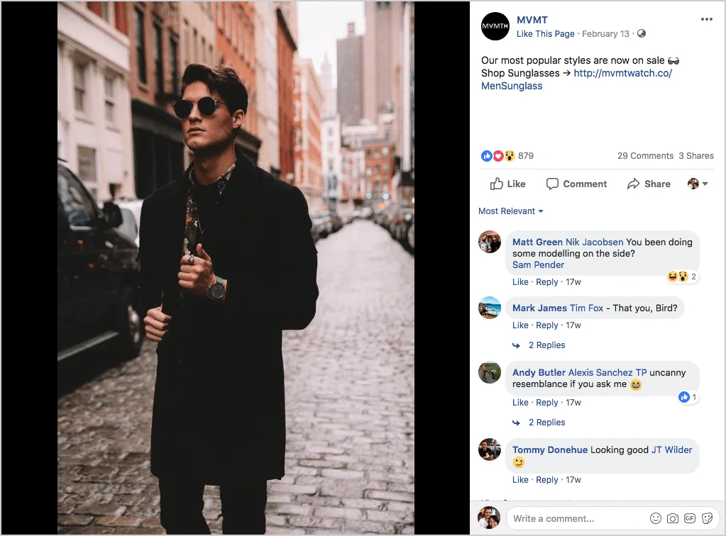 Man in sunglasses and coat walking down an urban street.
