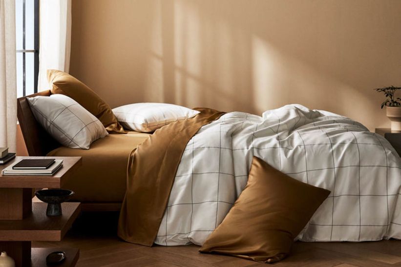 Modern bedroom with brown and white bedding and wooden furniture.