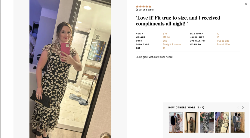 Woman taking mirror selfie in black and white dress with floral pattern.