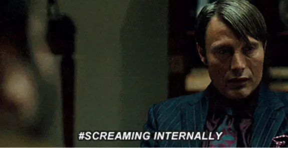 Man in a suit sitting with text 'screaming internally' overlay.