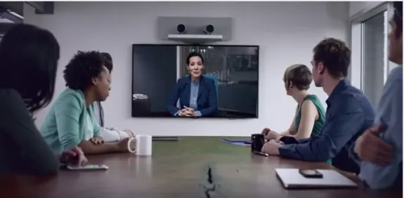 Team in office having a video conference meeting with a woman on screen.