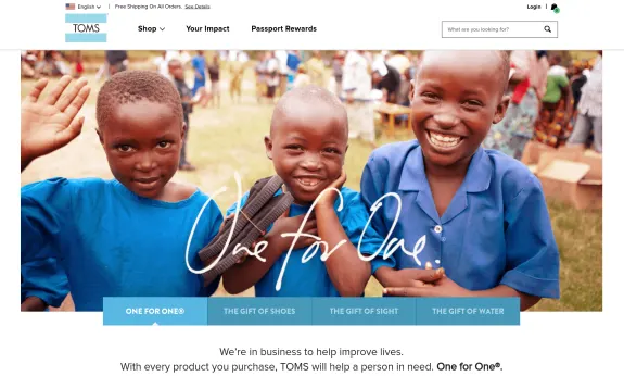 Smiling children in blue shirts, part of TOMS charity program, waving at the camera.