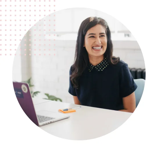 Smiling woman sitting at desk with laptop in office